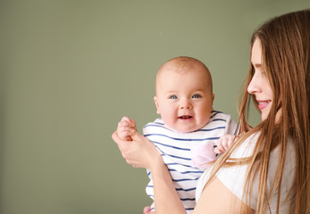 Happy mother with adorable baby girl on color background