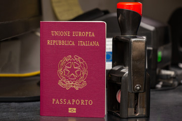 Red biometric passport of a Italian citizen with a border date stamper, close-up. Inscription -...