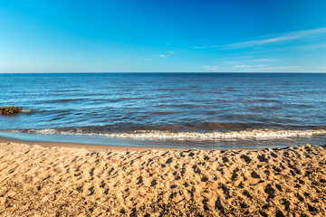 Sandy shore and blue water of a big lake on a hot day in summer