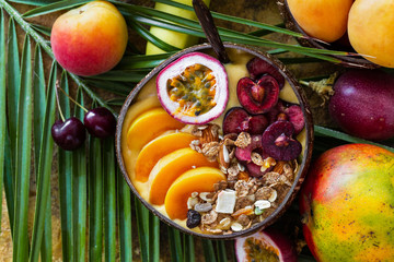 Naklejka na ściany i meble Smoothie bowl and exotic fruits on tropical palm leaves. Top view