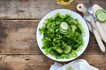 Vegetable salad with broccoli, cucumbers and lettuce in a white bowl 