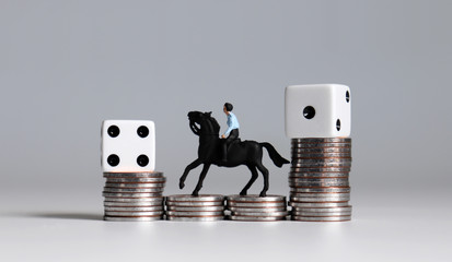 Miniature man riding a horse with two white dice on coin stacks. 