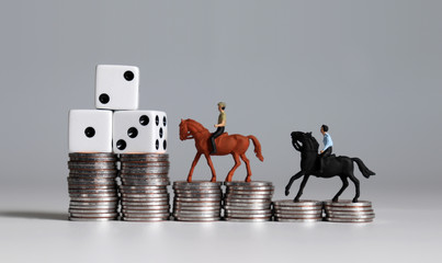 Two miniature men riding a horse with three white dice on coin stacks. 