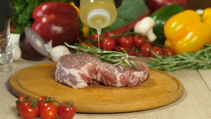 Big steak on a wooden board against a background of vegetables.