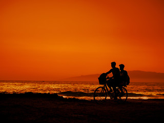 Fototapeta na wymiar Two friends are riding bicycle at sunset