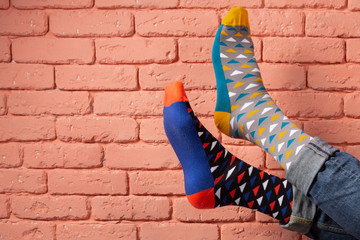 colored socks dressed on men's feet, on the background of pink brick wall, concept