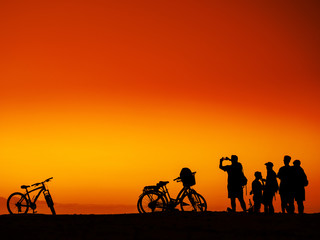 Fototapeta na wymiar Group of men with bicycles at sunset