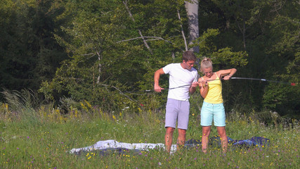 Young couple working together to set up a tent during a fun camping adventure © helivideo