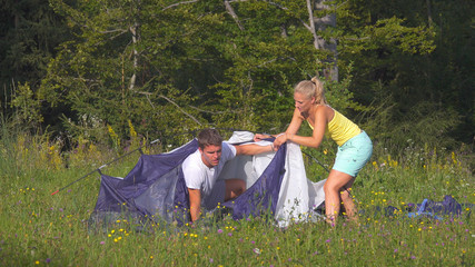 Young newlyweds arguing over how to set up the tent during a camping journey