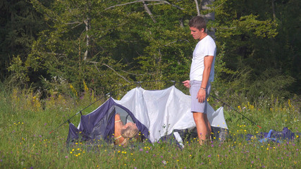 Young man gets annoyed as the tourist couple has problems setting up their tent.
