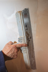 Man is priming a surface with a palett knife.  Maintenance repair works renovation in the flat....