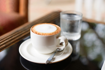 Cup of cappuccino coffee on the table at the cafe.