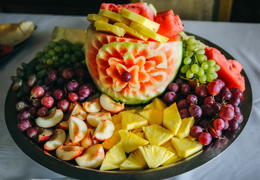 Fruit carving for wedding reception. Watermelon, peaches, grapes and pineapples are on the plate. Dessert for guests.