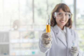 A young Asian woman scientist holding a test tube in a laboratory.