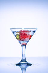 Strawberries in a glass with ice. Strawberry Cocktail. Frozen splashes of clean, spring water, in a glass with frozen strawberries, on a white background.