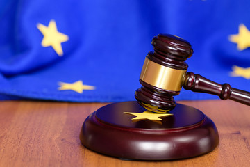 Сollapse of the European Union. UK exit from Europe. Justice and legality. Judge's gavel on the table and the EU flag in the background. Selective focus.