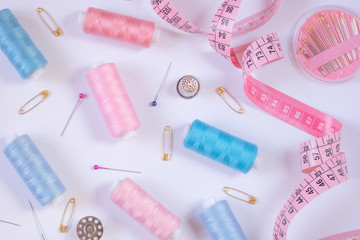 Sewing accessories for needlework in pink and purple and blue tones on white background