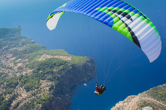 Paraglider flies over the sea and mountains. Extreme sport. Adrenalin. Beautiful view