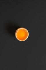 Single egg broken yolk view top. Black background text copy space.