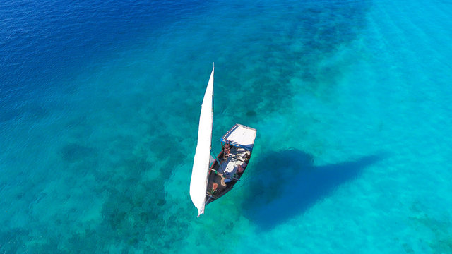 White sailboat in a sea of traditional Dhow Zanzibar island Nungwi Beach. Aerial view