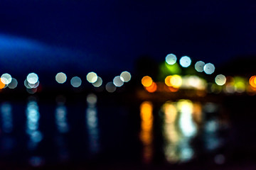 Night twilight blurred light gold bokeh reflecting on the sea surface water abstract background.