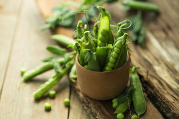 Vintage wooden surface for design with beautifully located pods of green peas.