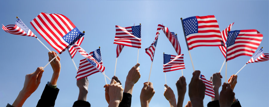 Group of People Waving American Flags over blue sky
