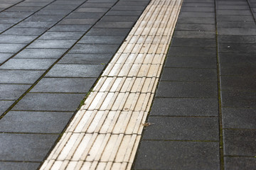 safety line on a pavement made of white and black stones at a railway station