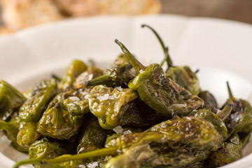 Green Padron Peppers with Crisp Bread in Rustic White Plate. Pimientos de Padrón.
