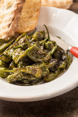 Green Padron Peppers with Crisp Bread in Rustic White Plate. Pimientos de Padrón.