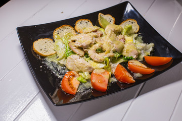 Caesar salad with bacon and quail eggs Black plate