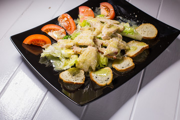 Caesar salad with bacon and quail eggs Black plate