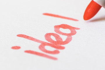 Handwritten inscription in red marker on white paper, photographed close-up. Macro photo suitable for background.