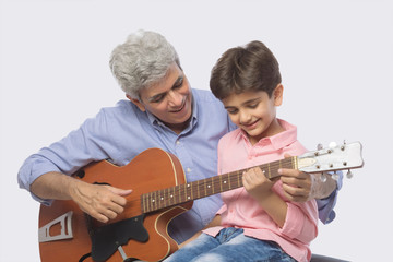 Grandfather and grandson playing guitar	