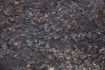 the texture of wet dark brown stone with moss. close-up of rock.
