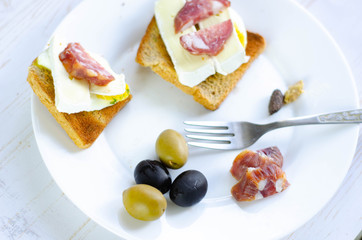 Simple breakfast on white background. Eggs, toast, olive, salami, cheese