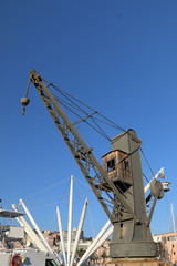 Fototapeta na wymiar An old crane for loading cargo ships inside the ancient port of Genoa