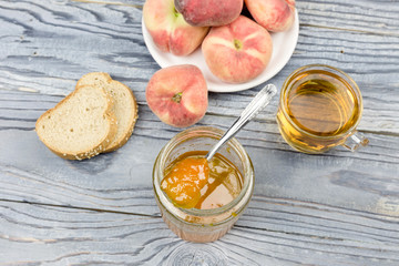 Peach jam, tea and bread close-up on a wooden table