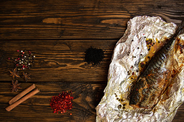 Baked mackerel with spices on a rough wooden background