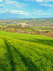 Fototapeta na wymiar green landscape on hills around Parma with lonely person sitting in grass field near Torrechiara castle and watching panorama, Italy