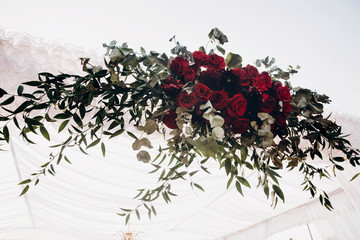 white and red arch and aisle at wedding reception in park, with red bouquet