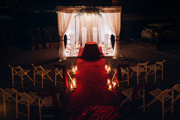wedding venue aisle with candles in glass lanterns and arch, stylish wedding decor for evening...