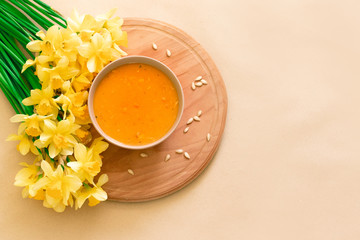 Pumpkin and carrot soup, tadka with cream and parsley on dark wooden background. Top view.
