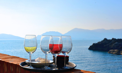 four glasses of white and red wine in front of the beach and romantic seaside, aperitif moment in Tellaro, Liguria Italy