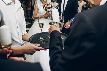 people toasting with champagne glasses at wedding reception, waiter serving on tray champagne drinks, celebration catering