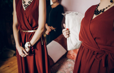 stylish bridesmaids with red and white flowers on boutonniere on hand and in red dress. beautiful...