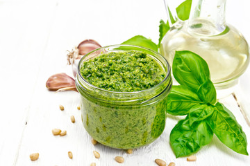 Pesto in glass jar on light wooden board