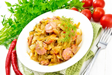 Cabbage stew with sausages in white plate on light board
