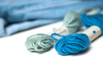 Fototapeta na wymiar closeup of blue cotton threads on white table on blue jeans background