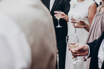 people toasting with champagne and wine glasses in hands at luxury wedding reception at restaurant. cheering at stylish celebration. luxury life concept. space for text